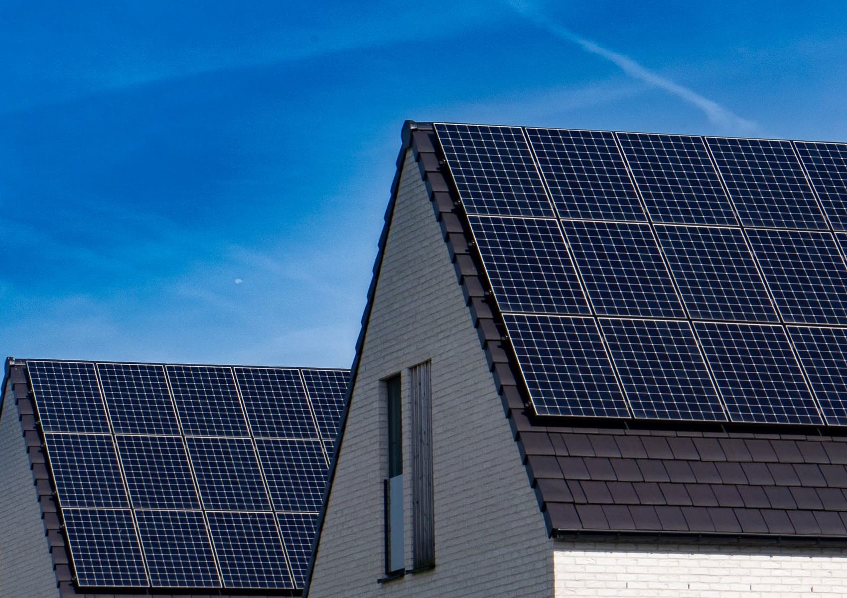 Satteldächer mit vollschwarzen Solarmodulen vor blauem Himmel